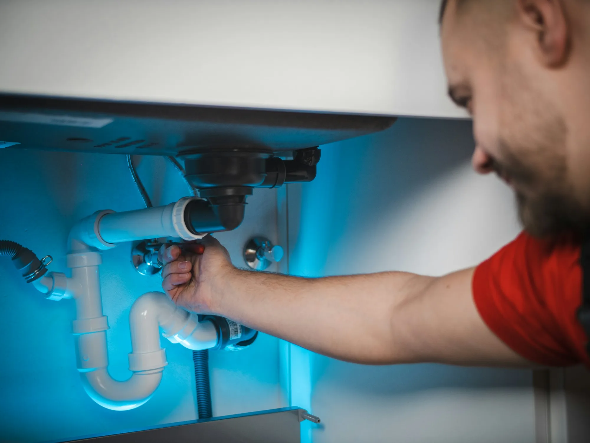 Plumber installing pipe fittings under a sink